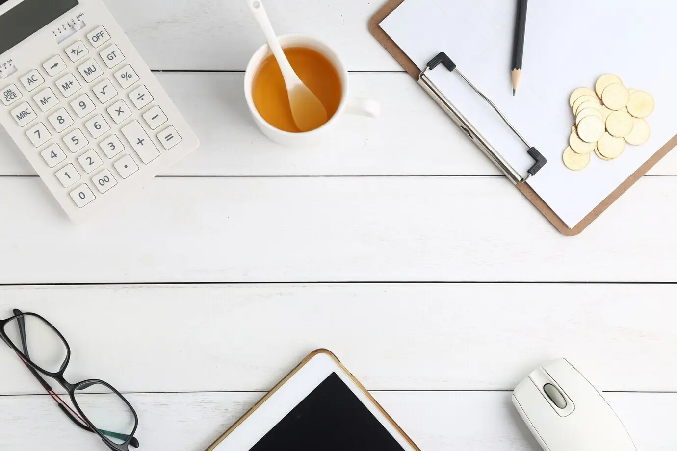 На белом опрятном столе — очки, калькулятор, монеты и планшет.